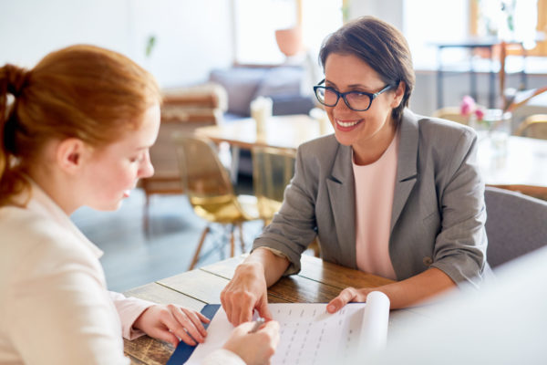 Applying for vacancy Smiling employer looking at applicant and showing her terms of contract