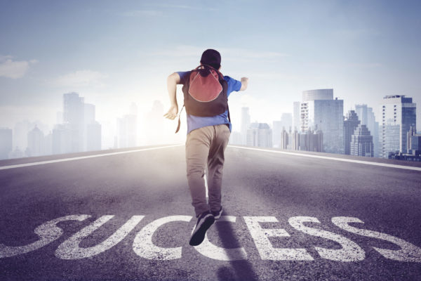 Back view of male student running on the road with Success text while carrying a backpack in the city